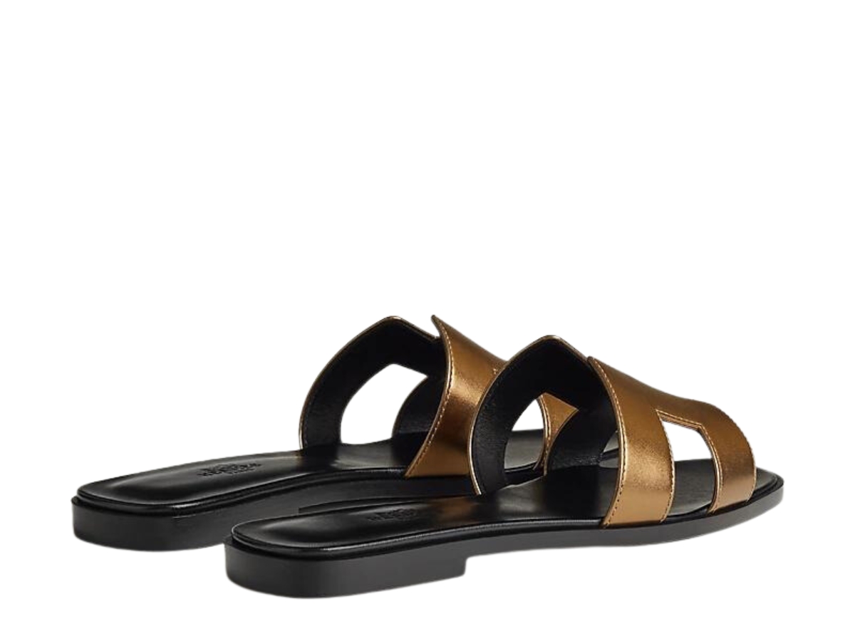https://d2cva83hdk3bwc.cloudfront.net/hermes-oran-sandal-in-calfskin-with-metallic-finish-and-iconic-h-cut-out-dore-fonce-3.jpg